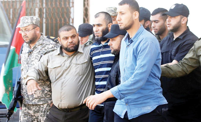 Security forces escort an alleged collaborator with Israel, center, who was convicted of killing senior Hamas commander Mazen Fuqaha, as he leaves a Hamas-run military court in Gaza City on May 21. (Reuters)