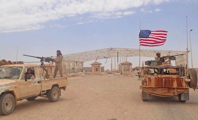 A US-backed anti-government Syrian fighter from Maghaweer al-Thawra (left) and an American soldier take their position at the Syrian-Iraqi crossing border point of Al-Tanf, south Syria on May 23, 2017. (Hammurabi's Justice News via AP)