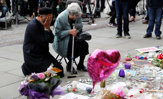 A Jewish woman named Renee Rachel Black and a Muslim man named Sadiq Patel react next to floral tributes in Albert Square in Manchester, Britain, on May 24, 2017. Following an interfaith show of unity in Manchester after Monday’s terror attack, Muslim groups in the UK have warned of an increase in Islamophobic hate crimes. (REUTERS/Darren Staples)