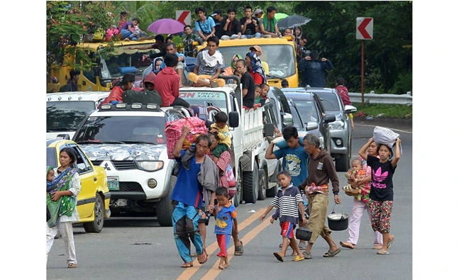 A family carrying their belongings walks in front of other residents in vehicles as they flee from Marawi on the southern island of Mindanao on Friday as fighting between Islamist militants and government forces continues. (AFP / Ted Aljibe)