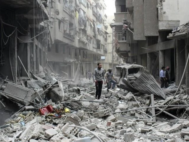FILE photo: People walk amid the rubble following reported air strikes by Syrian regime forces on May 14, 2015 on the rebel-held town of Ain Tarma, east of the capital Damascus. (AFP)