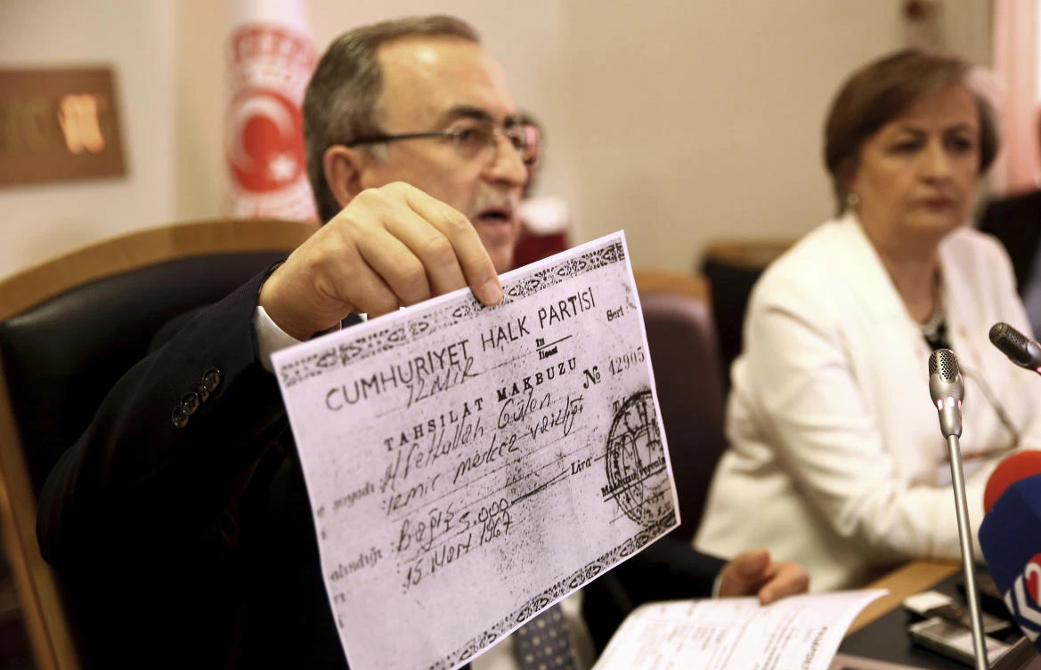 Resat Petek, the head of a Turkish parliamentary committee charged with investigating the coup attempt, shows a document linking US-based Fethullah Gulen's financial connection with Turkey's opposition party during a press conference in Ankara, on Friday. (AP)