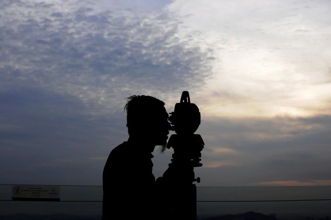A man looks through a telescope to view the new lunar month to see when Ramadan has started. Authorities in Belgrade removed a mosque they deemed illegal ahead of the start of the holy month. (AP)