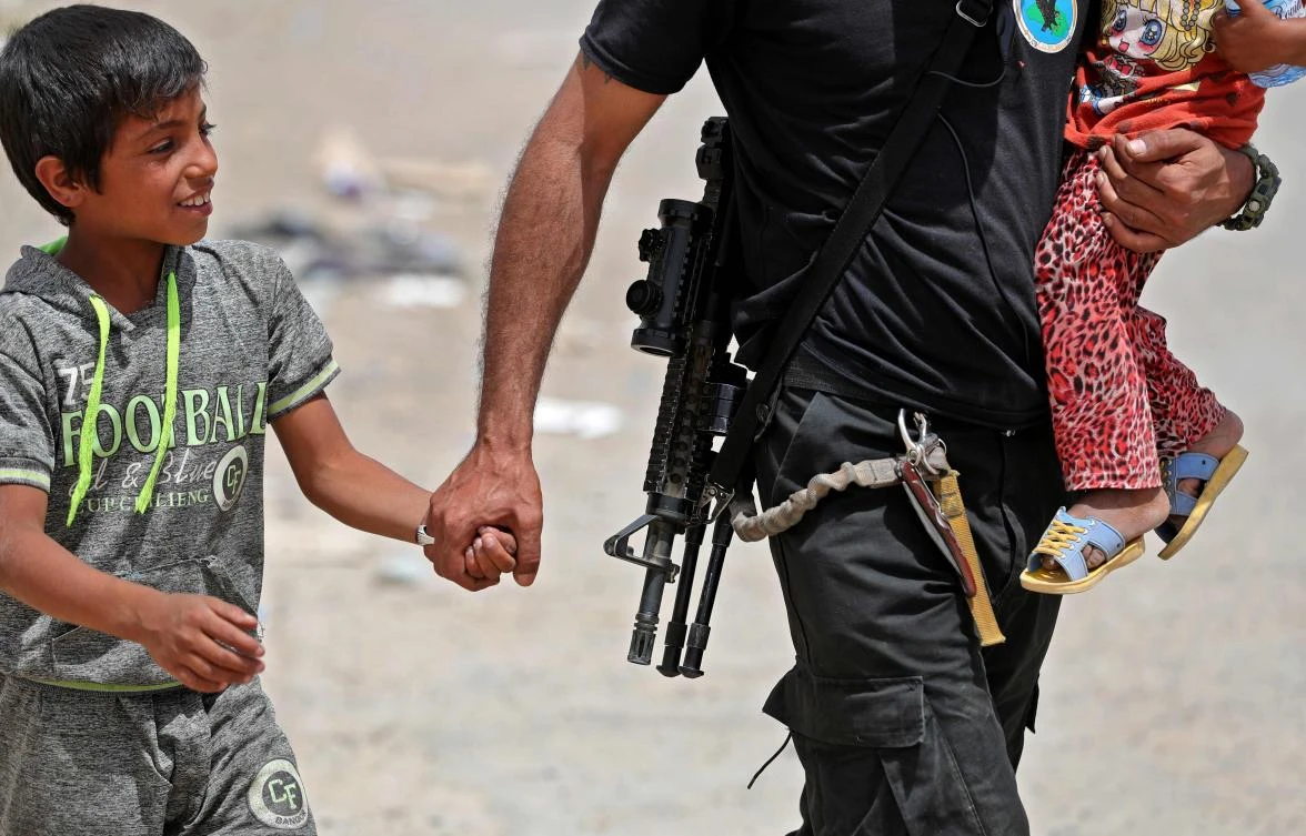 An Iraqi soldier helps displaced children after leaving their homes west of Mosul on May 26, 2017, as government forces continue their offensive against Daesh. (AFP)
