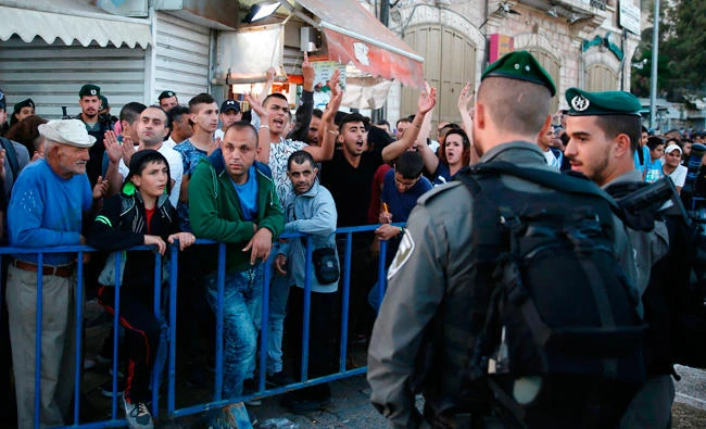 Palestinian demonstrators are separated by Israeli police barriers from Israelis celebrating 50 years of Jewish state control of Jerusalem's Old City on May 24, 2017. Israel on Sunday approved plans to install a cable car to Jerusalem's Old City, a project likely to anger Palestinians and much of the international community. (AFP / AHMAD GHARABLI)
