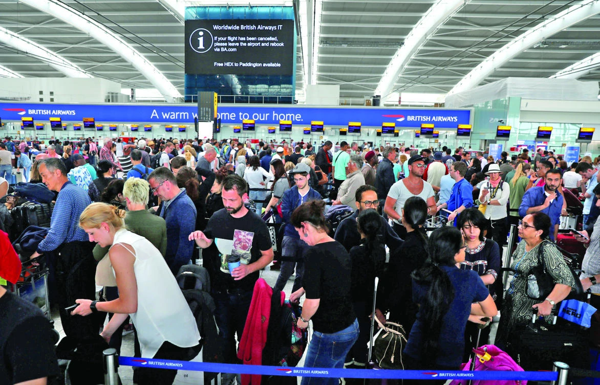 People wait with their luggage at the British Airways check-in desks at Heathrow Terminal 5 in London. (Reuters)