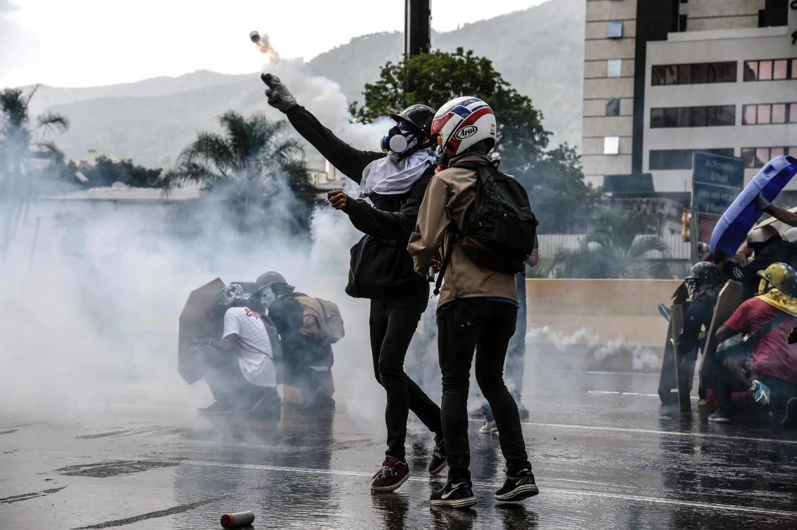 An opposition demonstrator hurls a tear gas canister back at riot police during a protest against the government of President Nicolas Maduro in Caracas. (AFP)