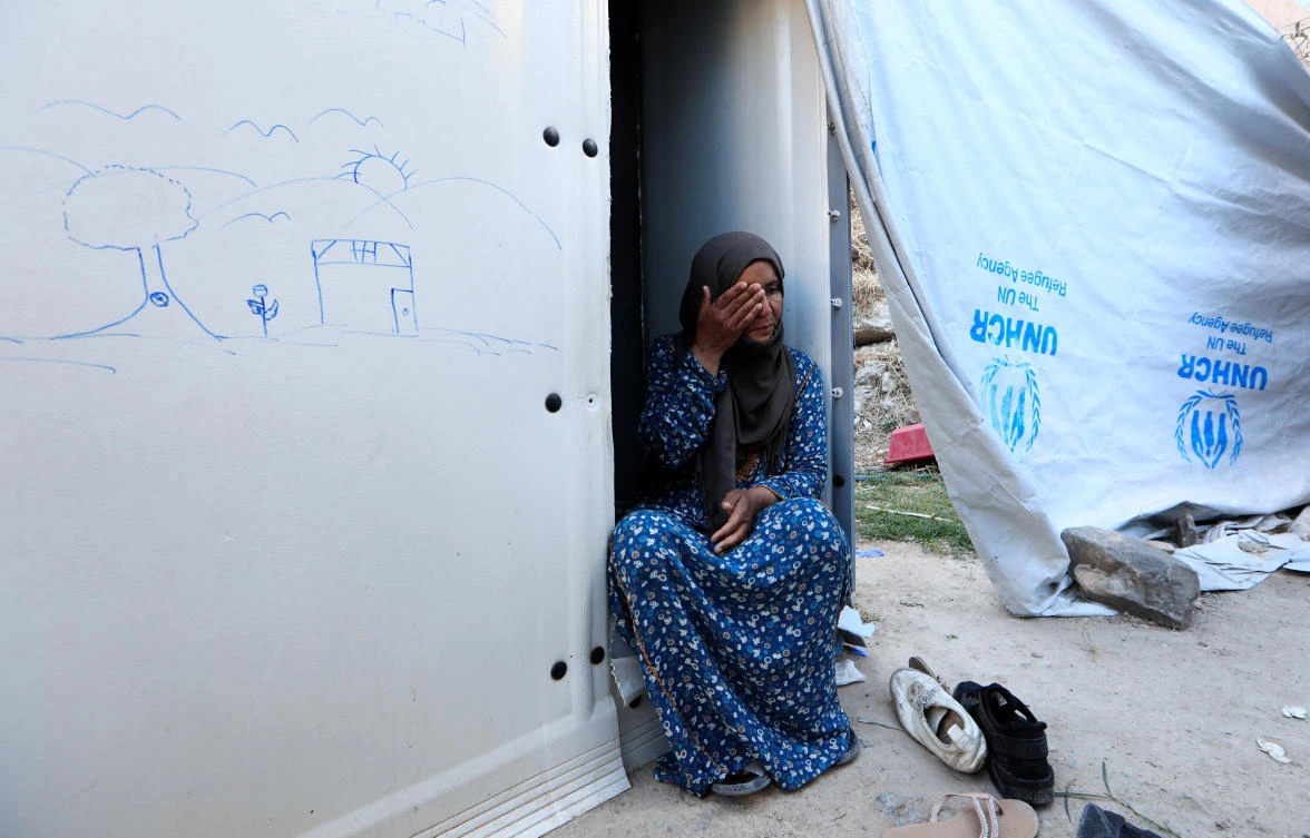 Aanoud, 47, from Deir Ezzor in Syria sits beside her shelter at the Souda refugee camp in Chios Island, Greece, June 10, 2017. (Reuters)