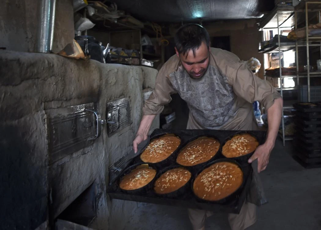 An Afghan baker bakes cakes ahead of the Eid al-Fitr festival, which marks the end of Islamic holy month of Ramadan, at a traditional sweets factory in Kabul on June 23, 2017. Muslims around the world are preparing to celebrate the Eid al-Fitr holiday, which marks the end of the fasting month of Ramadan. / AFP / WAKIL KOHSAR