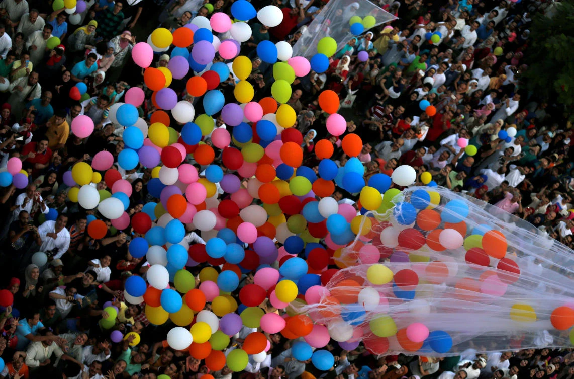 Egyptians celebrate and try to catch balloons released after Eid al-Fitr prayers, marking the end of the Muslim holy fasting month of Ramadan at a public park, outside El-Seddik Mosque in Cairo, Egypt June 25, 2017. REUTERS/Amr Abdallah Dalsh