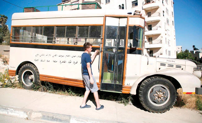 Palestinian youth Mohammed Nassar opens the door of a restored pre-1967 bus, called ‘Bus 47,’ which bears writing in Arabic of the names of the cities it used to visit. It is parked on the side of a street in the Israeli occupied west Bank city of Ramallah. Nassar and other youngsters are trying to preserve the memory of the exodus — and life before it — by restoring the bus, which used to transport Palestinians across the Middle East prior to the 1967 Six-Day war. (AP)