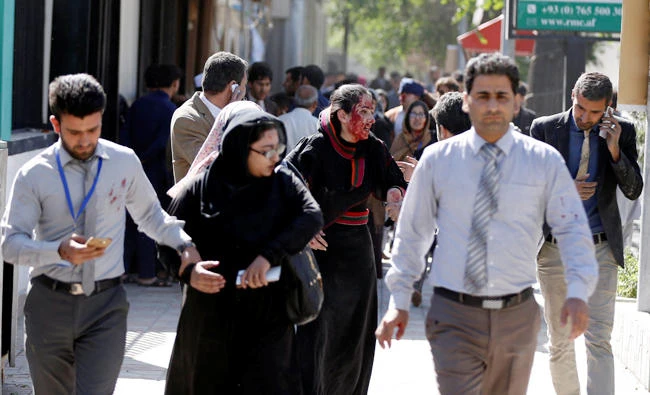 Injured Afghans run from the site of a blast in Kabul on Wednesday. (Reuters)