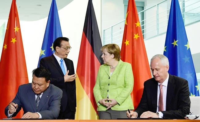 Xu Heyi, chairman of the BAIC Group, and Hubertus Troska, CEO of Daimler Greater China Ltd. and board member of the Daimler AG, sign an economic agreement in Berlin on Thursday in the presence of German Chancellor Angela Merkel and Chinese Prime Minister Li Keqiang. (AFP)