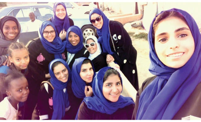 Lina Tahlawi, founder of the Bassmat Al-Badr non-profit organization, poses with a group of young volunteers during the distribution of iftar meals to needy people.(AN photo)
