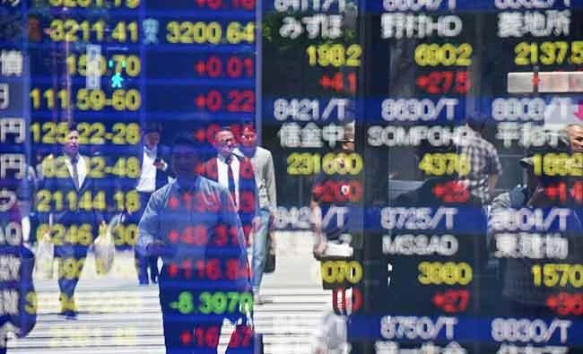 Pedestrians are reflected on a stock quotation board of the Tokyo Stock Exchange in Tokyo on Friday. (AFP)