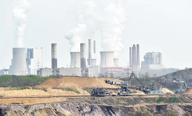 In this April 3, 2014 file photo giant machines dig for brown coal at the open-cast mining Garzweiler in front of a smoking power plant near the city of Grevenbroich in western Germany. (AP)