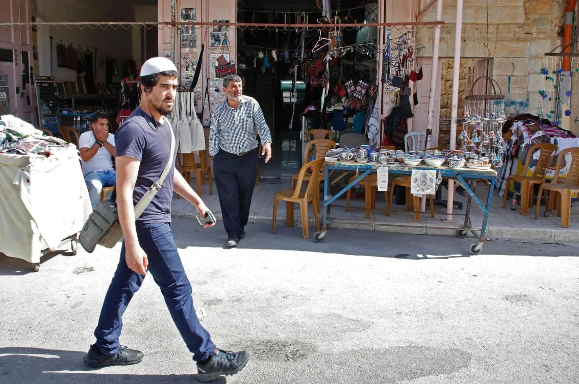 An Israeli settler walks past a Palestinian shop in the old city of Hebron. (AFP)
