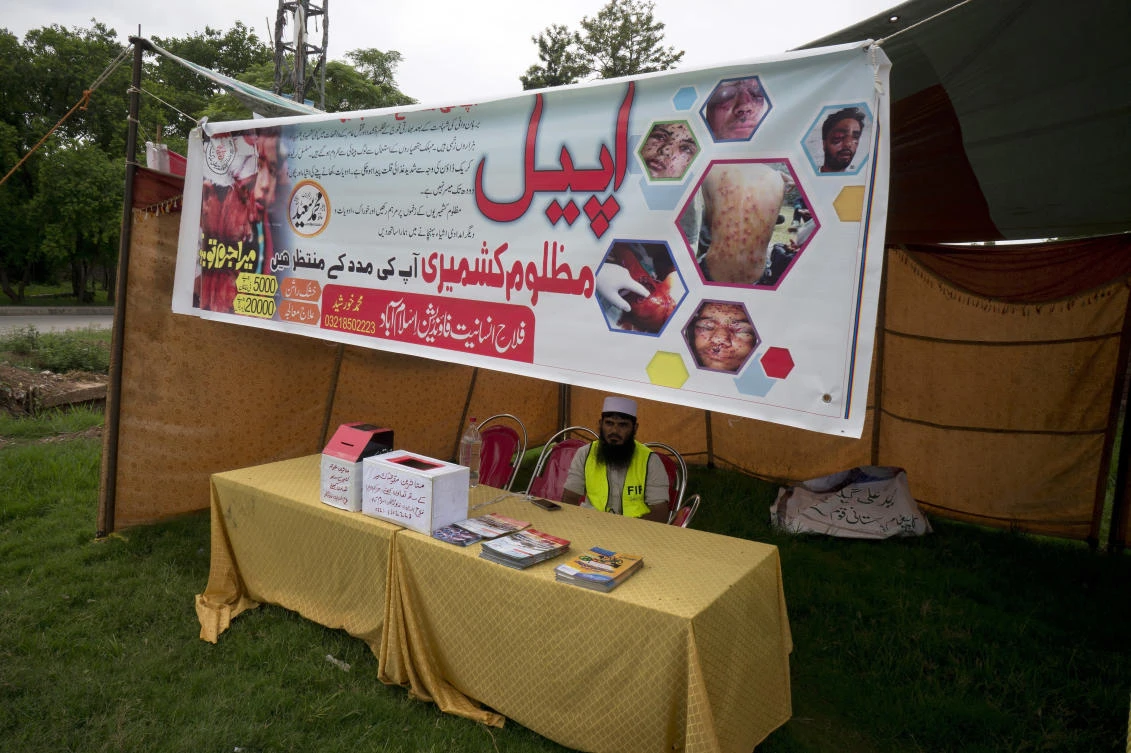In this Aug. 2, 2016 file photo, a worker sits in stall set up by the charity Falah-e-Insaniat Foundation, waiting for donations for Indian Kashmiris, in Islamabad, Pakistan. (AP Photo/B.K. Bangash, File)