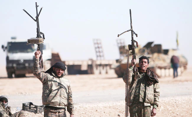 Syrian Democratic Forces fighters hold up their weapons in the north of Raqqa city, on Saturday. (Reuters)