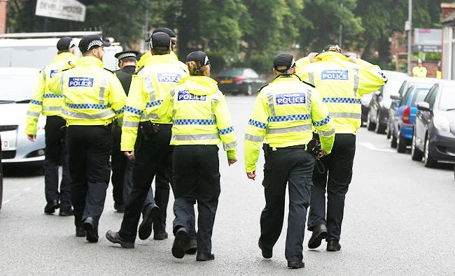 Police walk up the street towards Devell House, in Rusholme, Manchester, Britain on Friday. (REUTERS)