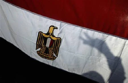 The shadow of a demonstrator making a peace sign is cast on an Egyptian flag. (REUTERS)