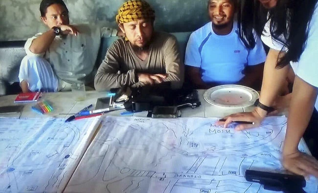 This image taken from undated video shows the purported leader of the Daesh group Southeast Asia branch, Isnilon Hapilon, center, at a meeting of militants at an undisclosed location. The images offer a rare glimpse into the clandestine operations of insurgents who followed through two weeks ago with an unprecedented assault on the lakeside city of Marawi, parts of which they still occupy today. (Photo via AP)