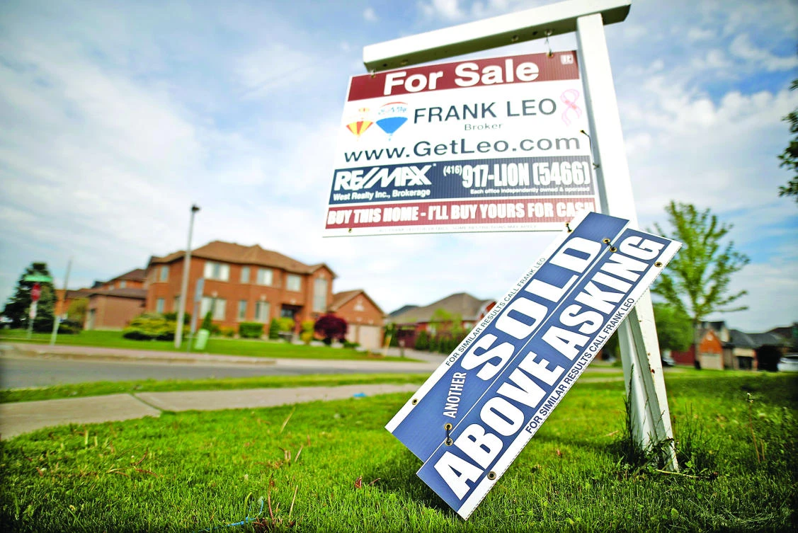 A real estate sign that reads “For Sale” and “Sold Above Asking” stands in front of house in Vaughan, a suburb in Toronto, Canada, in this May 24 file photo. (Reuters)