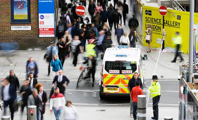 People pass a police van at a closed street in the London Bridge area of London on Tuesday. (AP)
