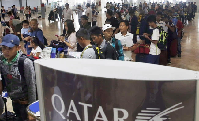 Overseas Filipino Workers (OFWs) queue up at Qatar Airways check-in counter in Manila for the scheduled flight to Doha on Wednesday. (AP Photo/Bullit Marquez)