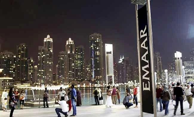People have their photos taken near an Emaar sign outside the Dubai Mall in this March 15, 2014 file photo. (Reuters)