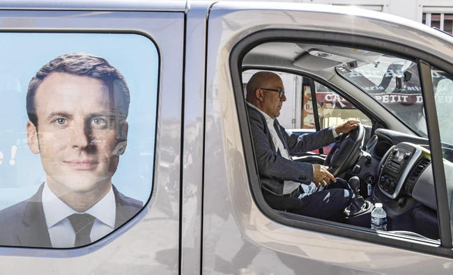 Bruno Bonnell, right, candidate of "La Republique en marche" party for the upcoming legislative elections in the Rhone department, drives his truck bearing a picture of French President Emmanuel Macron during a campaign visit in Villeurbanne, on Thursday. (AFP)