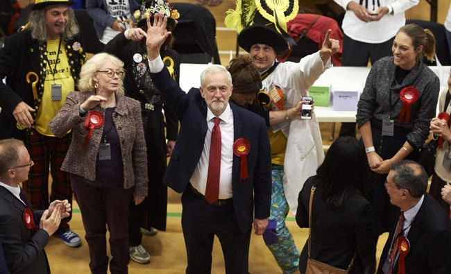 A smiling Jeremy Corbyn (C), Labour party leader, waves after arriving at the count center in Islington, London, early Friday, hours after the polls closed in Britain's general election. (AFP / NIKLAS HALLE'N)