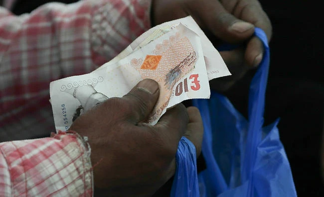 In this file picture taken on April 11, 2017 a trader holds ten pound sterling notes as a customer pays for goods at Whitechapel Market in east London. (AFP / DANIEL LEAL-OLIVAS)