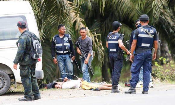 In this March 6, 2013 photo, Malaysian police arrest two men suspected to be among the 200 Islamic militants from the southern Philippines who invaded the Malaysian state of Sabah on Borneo island. Nine of the Filipinos have been sentenced to hang.(REUTERS/Bazuki Muhammad)