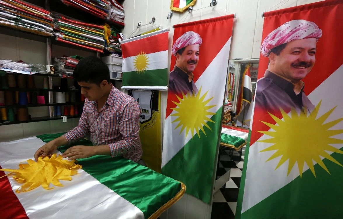 A man sews an Iraqi Kurdish flag bearing a portrait of Iraqi Kurdistan president Massud Barzani. (AFP)