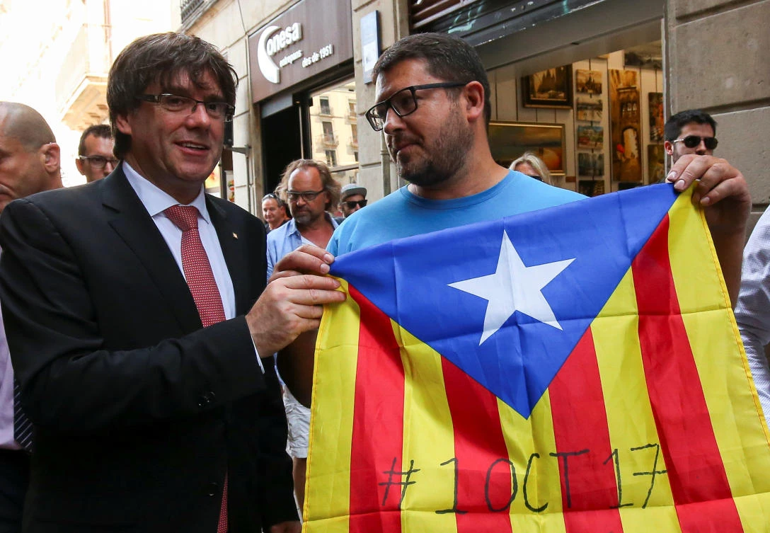 Catalonia’s regional President Carles Puigdemont poses next to a pro-independence supporter with a Catalan Estelada flag showing the date for which the regional government called for a referendum on a split from Spain, in Barcelona, on Friday. (Reuters)