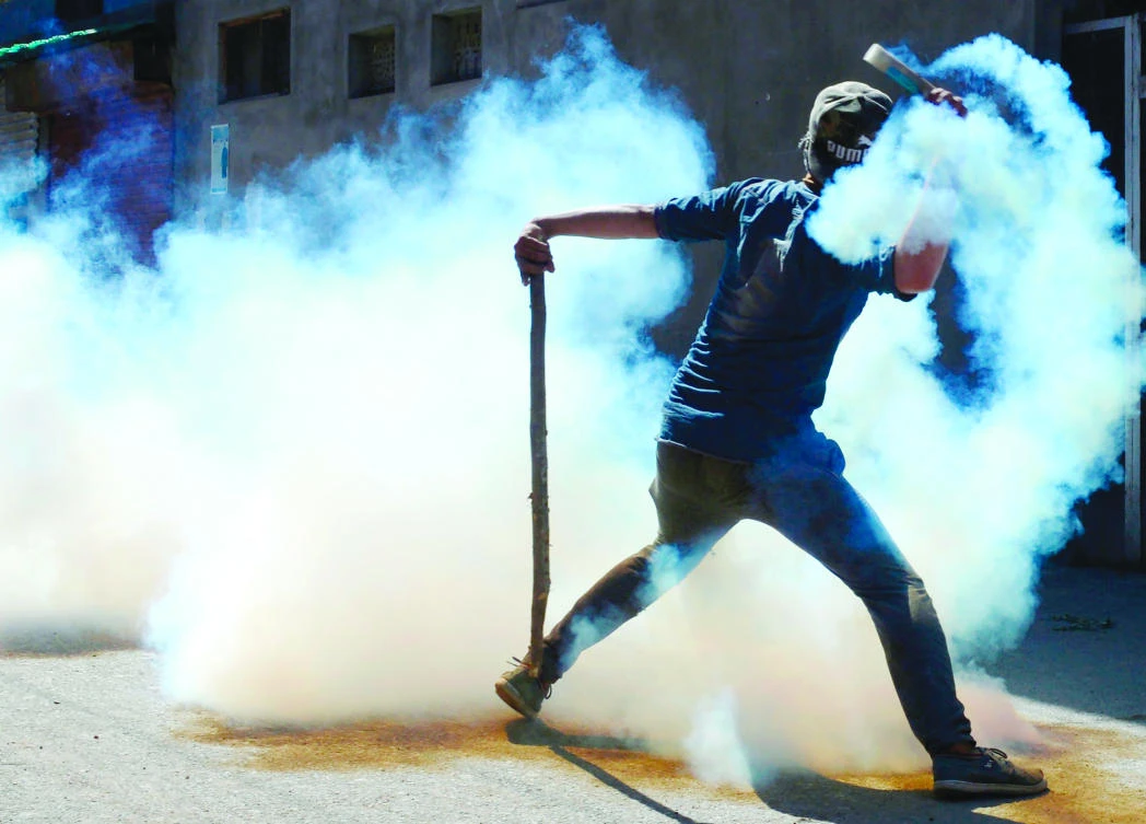 A Kashmiri protester throws back a teargas canister at Indian troops during clashes in Srinagar on Friday. (AFP)