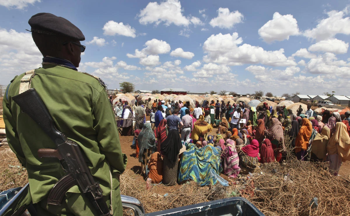 A policeman provides security as displaced people gather outside their makeshift shelters at a camp in Baidoa, Somalia, recently. (AP)