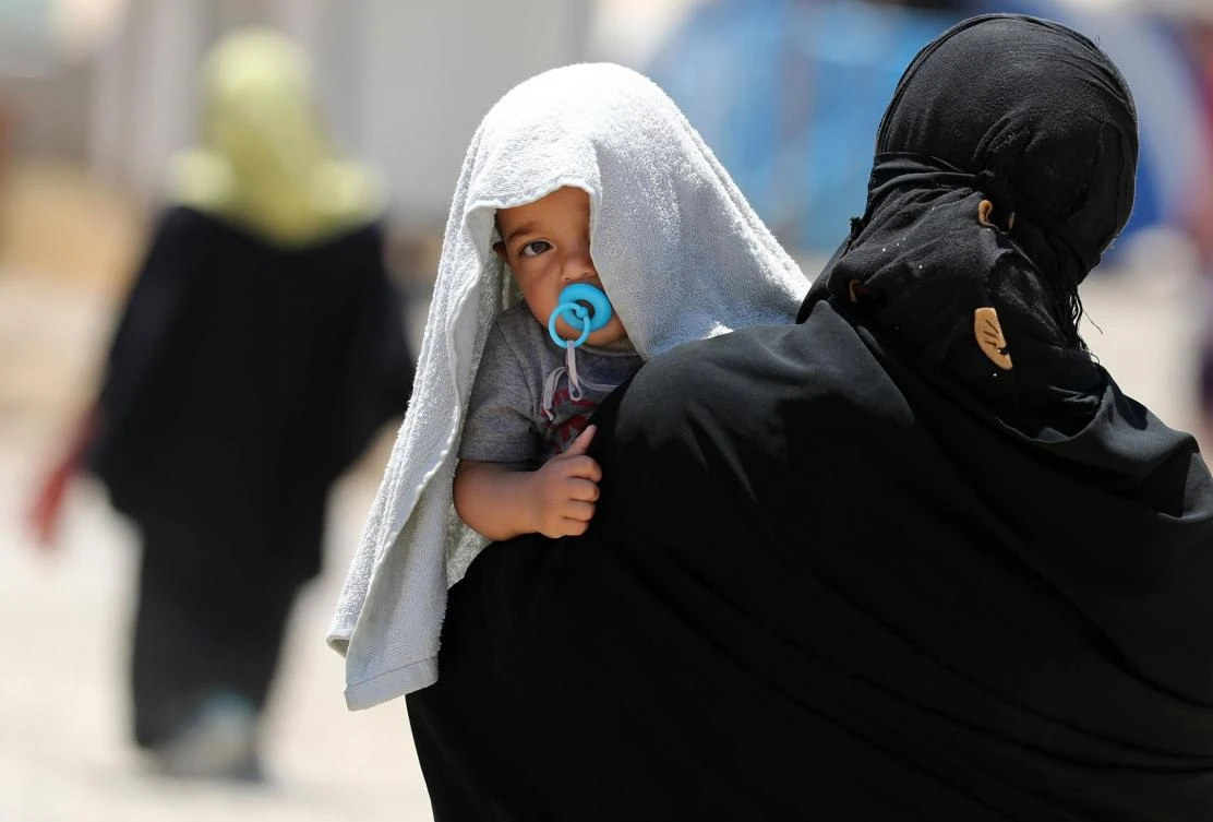 A picture taken on June 5, 2017 shows a displaced Iraqi woman carrying a child at the Al-Khazir camp for internally displaced people, located between Arbil and Mosul. Tired and traumatised, Iraqi mothers who fled Mosul struggle to breastfeed or buy baby formula milk for their babies. (AFP)