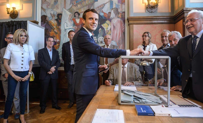 French President Emmanuel Macron casts his ballot next to his wife Brigitte Macron at a polling station in Le Touquet on Sunday. (AFP)