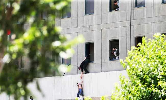 A man hands a child to a security guard after an assault on the parliament building in Tehran, Iran, in this June 7, 2017 photo. (AP)