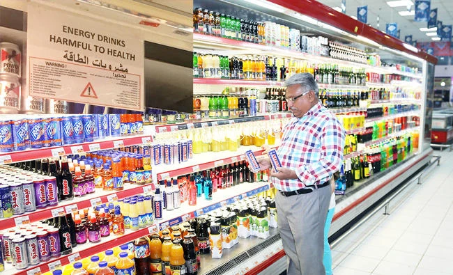 A man looks at an energy drink at a supermarket in Dammam. (Inset) ‘This product does not have any health benefits’ — new health warning of energy-drinks shelves as excise tax hits market. (AN photos by Imran Haider & Lulwa Shalhoub)