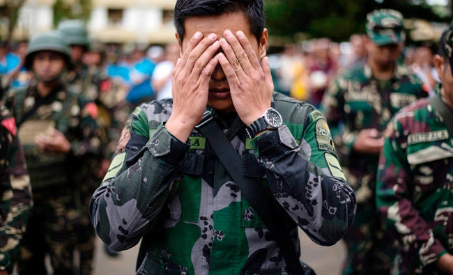 A soldier prays during a flag raising ceremony at the Lanao Del Sur provincial capital of Marawi on the southern island of Mindanao on Monday. Embattled Philippine troops struggling to force out Islamist militants from a southern city raised the national flag for Independence Day on June 12, in a tearful ceremony dedicated to the scores killed during the conflict. (AFP / NOEL CELIS)