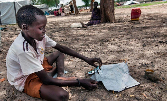 A displaced child makes toy tent while waiting for his family to build their settlement in Aburoc, South Sudan. (AFP)