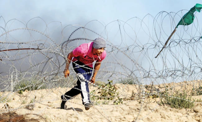A Palestinian protester runs for cover during clashes with Israeli troops near the border between Israel and Central Gaza Strip in this June 2 photo. (Reuters)