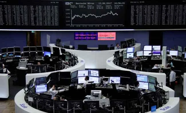 Traders work in front of the German share price index, DAX board, at the stock exchange in Frankfurt, Germany, on Tuesday. (REUTERS)
