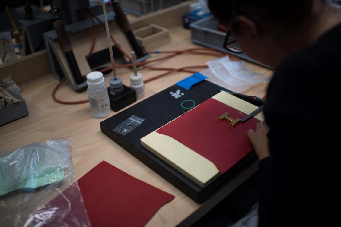 (FILES) This file photo taken on June 08, 2017 shows an employee working on a leather wallet at the Hermes new leather workshop in Saint-Junien, central France. They are exporting more and more, see globalization through rose-tinted glasses and create jobs without interruption : the French champions of luxury are an exception in the French economy, as evidenced by new hires announced at Hermes. (AFP)