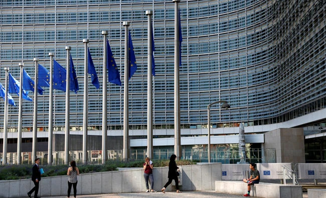 Flags flutter outside the European Commission headquarters in Brussels, Belgium, on Wednesday. The EU on Wednesday said it is slapping sanctions on three member states for refusing to take their share of refugees. (REUTERS/Francois Lenoir)
