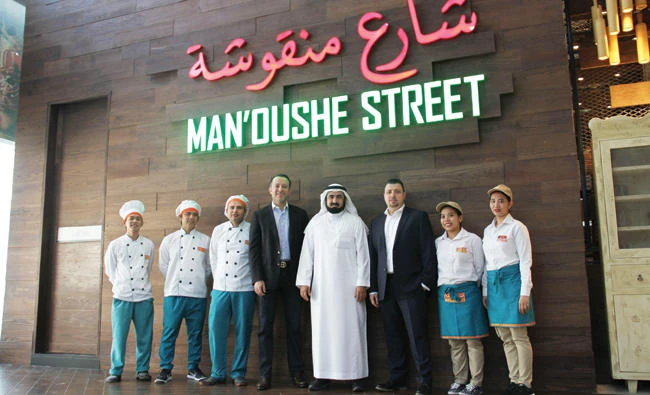Khalid Abdullah Al-Rajhi poses with Jihad Al-Eit, CEO of Man’oushe Street,
and his team during an event.