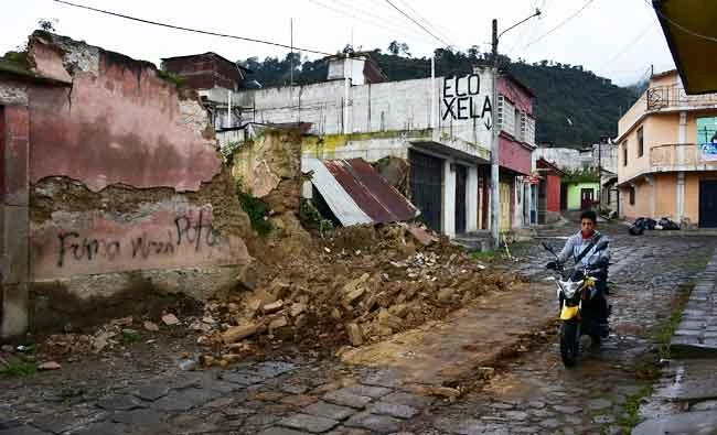 A resident rides a scooter past a collapsed wall after an earthquake in Quetzaltenango, Guatemala, on Tuesday. (REUTERS)